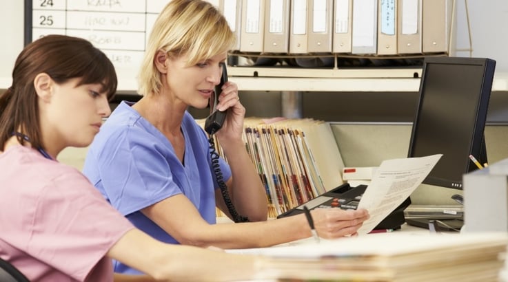 two nurses doing paperwork at a nurse's station