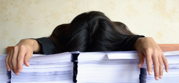 young business woman overwhelmed by several stacks of reports