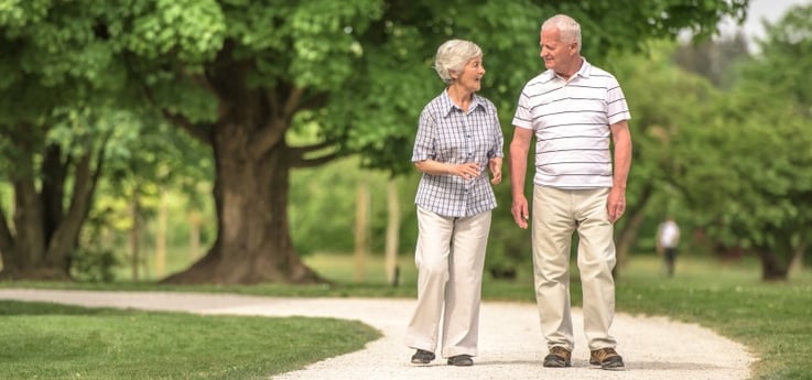 senior couple walking and talking on a gravel path outdoors