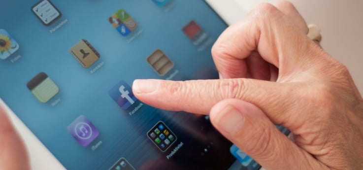 older woman's hands holding an iPad and using social media