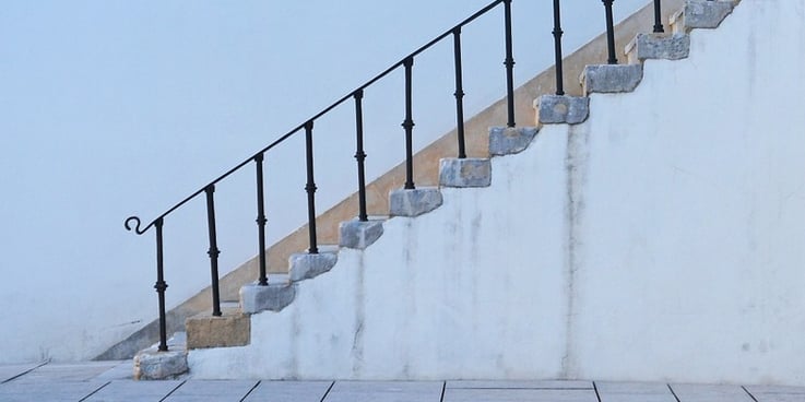 white staircase against a white wall, with wrought-iron railing